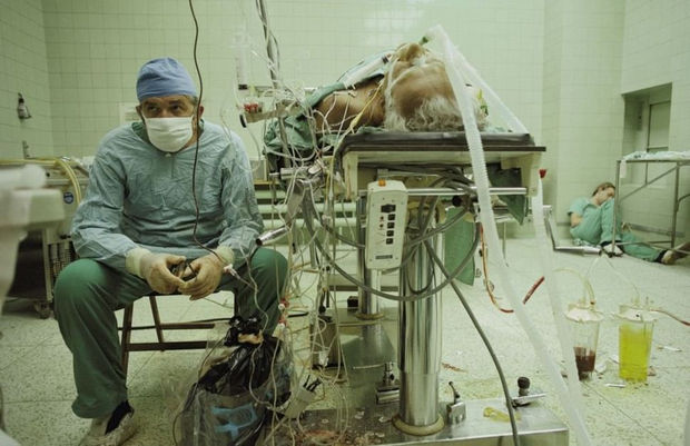 29 Powerful Pictures - In 1987, Dr. Religa monitors his patient's vitals after a intensive 23-hour long heart transplant surgery. His assistant is resting in the corner.