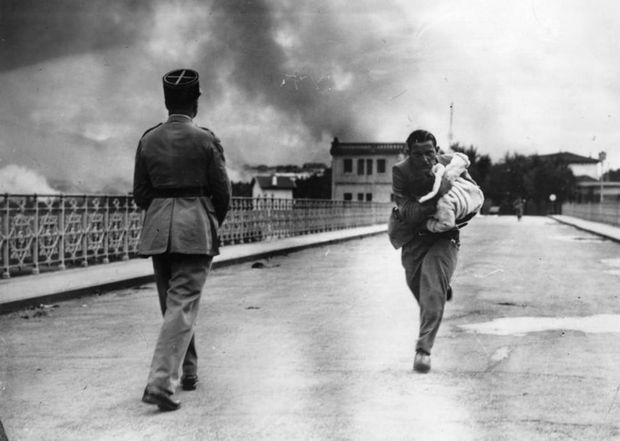 29 Powerful Pictures - During a civil war in 1936, a journalist dashes across a bridge to rescue a baby.
