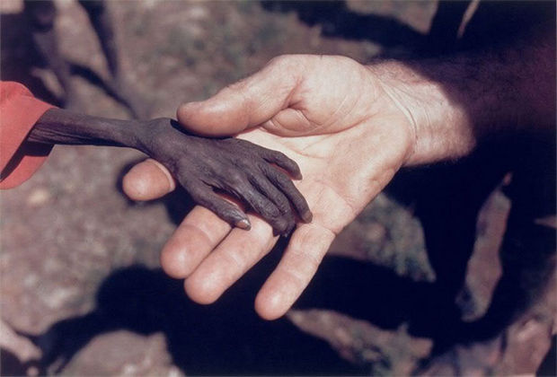 29 Powerful Pictures - Starving child in Uganda holding hands with a missionary.