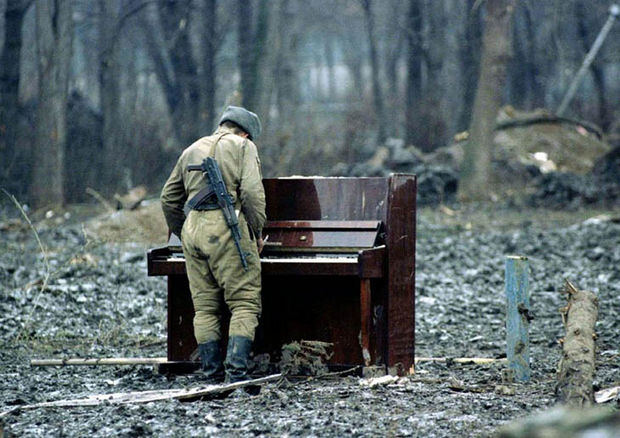 29 Powerful Pictures - In 1994, a Russian soldier plays an abandoned piano in Chechnya.