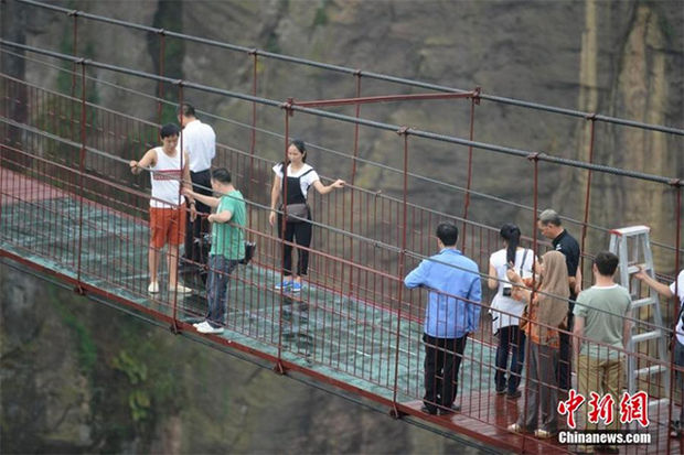 Glass Bridge in China - There are actually staff that help tourists cross the glass section and give them encouragement to make it across.
