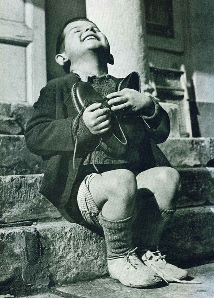 21 Historical Photos - A six year-old boy at an orphanage in Austria hugs his new pair of shoes given to him by the American Red Cross during World War II.