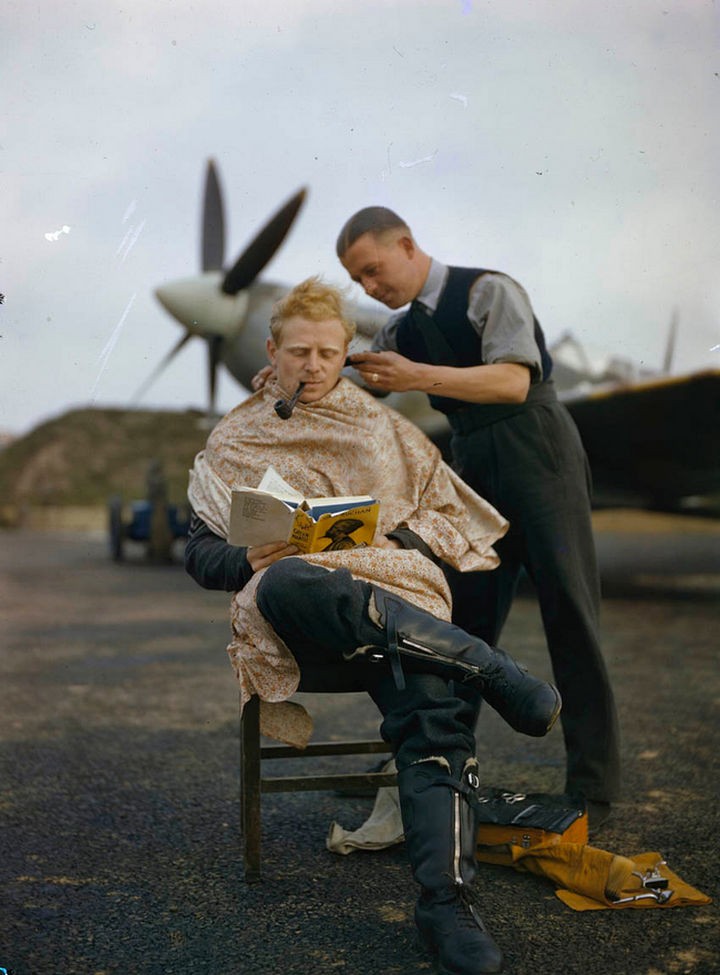 58 Colorized Photos from the Past - An RAF pilot getting a haircut between missions while reading a book.