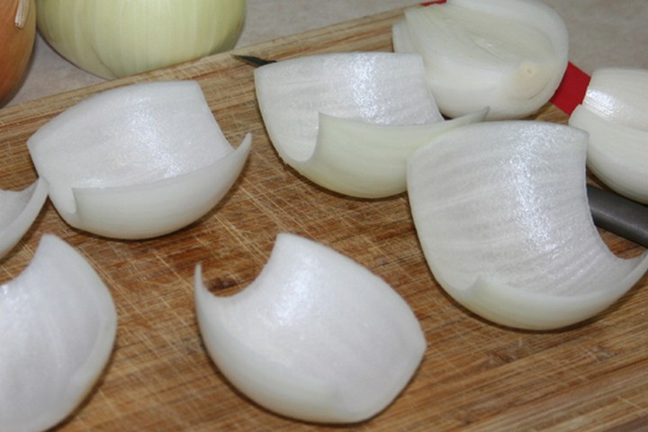 Begin by peeling the onions and cutting each one in half to make onion "petals" which we'll use to wrap around each meatball.