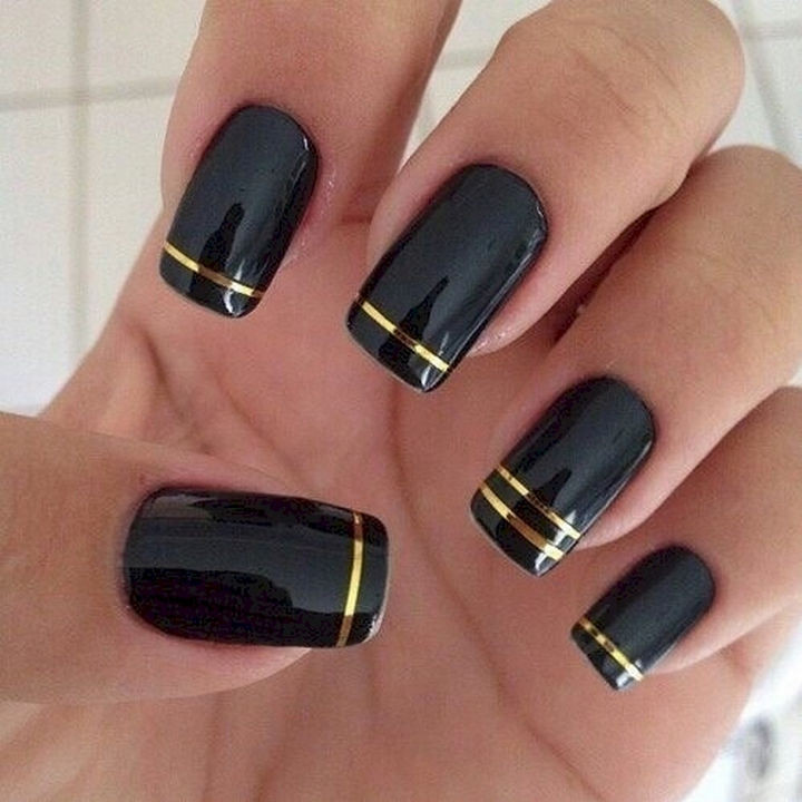 22 Black Nails That Look Edgy and Chic - Elegant gold striped nails.