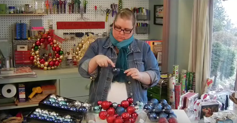She Begins Putting Christmas Ornaments on a Wire Hanger. Her Project Looks so Great You’ll Want to Make One Too!