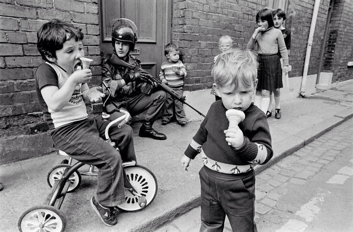 35 Rare Historical Photos - 1979: Children eat their ice cream cones while soldiers patrol the streets of Londonderry in Northern Ireland.