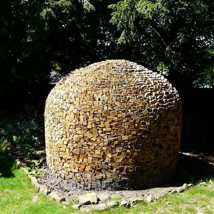 13 Displays of Stacked Wood Art - A log pile shaped like a bee hive.