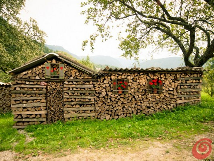 13 Displays of Stacked Wood Art - This wooden log home looks especially cute.
