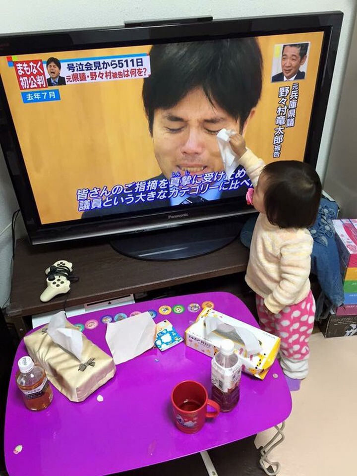 A toddler wiping away tears from a man crying on television.